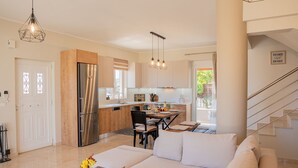 Eine moderne Küche mit einem Edelstahl-Kühlschrank, Holzschränken und einem Essbereich mit Tisch und Stühlen.