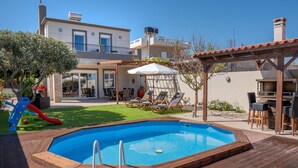 Ein Garten mit Swimmingpool, Holzterrasse und einer Terrasse mit Gartenmöbeln.