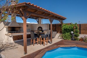 An outdoor patio with a pool, a barbecue area, and a wooden pergola. - Rodanthi Cretan Villa (Hersonissos)