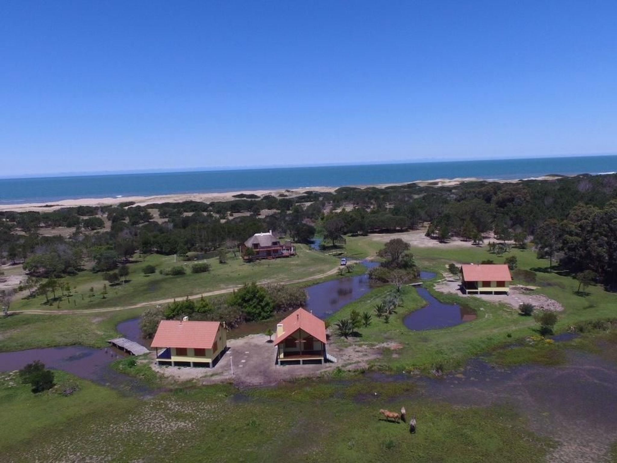 A coastal property with multiple houses, a beach, and a clear view of the ocean.