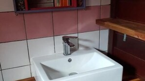 Un baño con un lavabo blanco, estantes de madera y un espejo.
