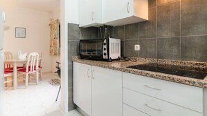 Een koelkast, een magnetron, een oven, kookgerei, borden en bestek