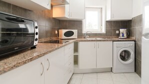 Een koelkast, een magnetron, een oven, kookgerei, borden en bestek