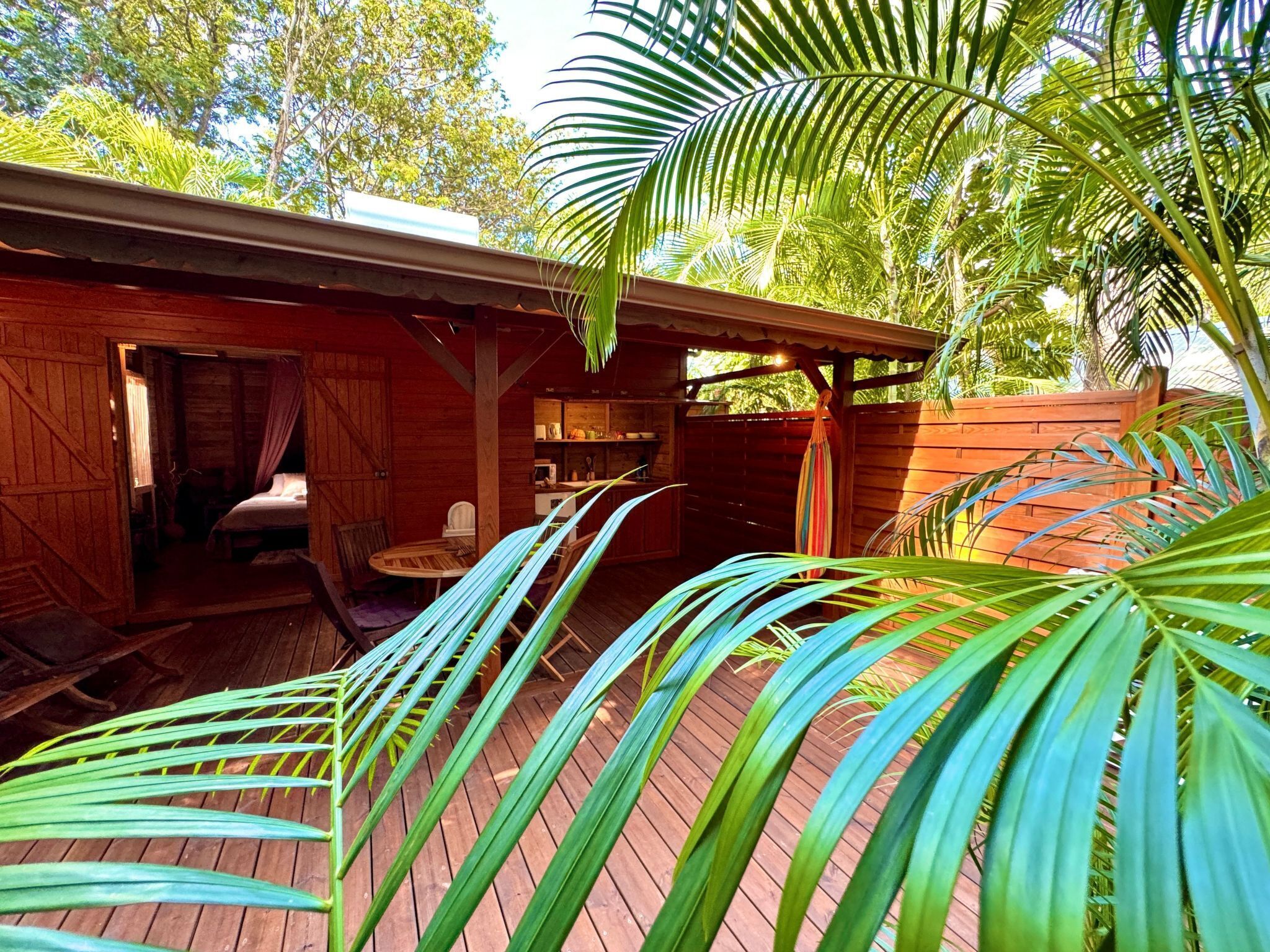 A wooden cabin with a bed, a small table, and a chair in the open area.