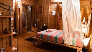 Une pièce chaleureuse, aménagée dans un chalet en bois, avec un lit, un banc et une petite table.