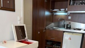 A compact kitchen with a white countertop, a built-in oven, a sink, and a refrigerator. - Naousa Center Living (Paros)