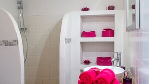Un baño con una bañera blanca, ducha y lavamanos con toallas rosas.
