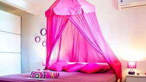 Un dormitorio con cama con dosel, una mesita de noche con lámpara y aire acondicionado instalado en la pared.