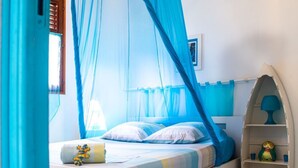A bed with a canopy, a bedside table with a lamp, and a shelf with decorative items.