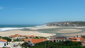 Une ville côtière avec des bâtiments construits sur une colline, une plage et l’océan.