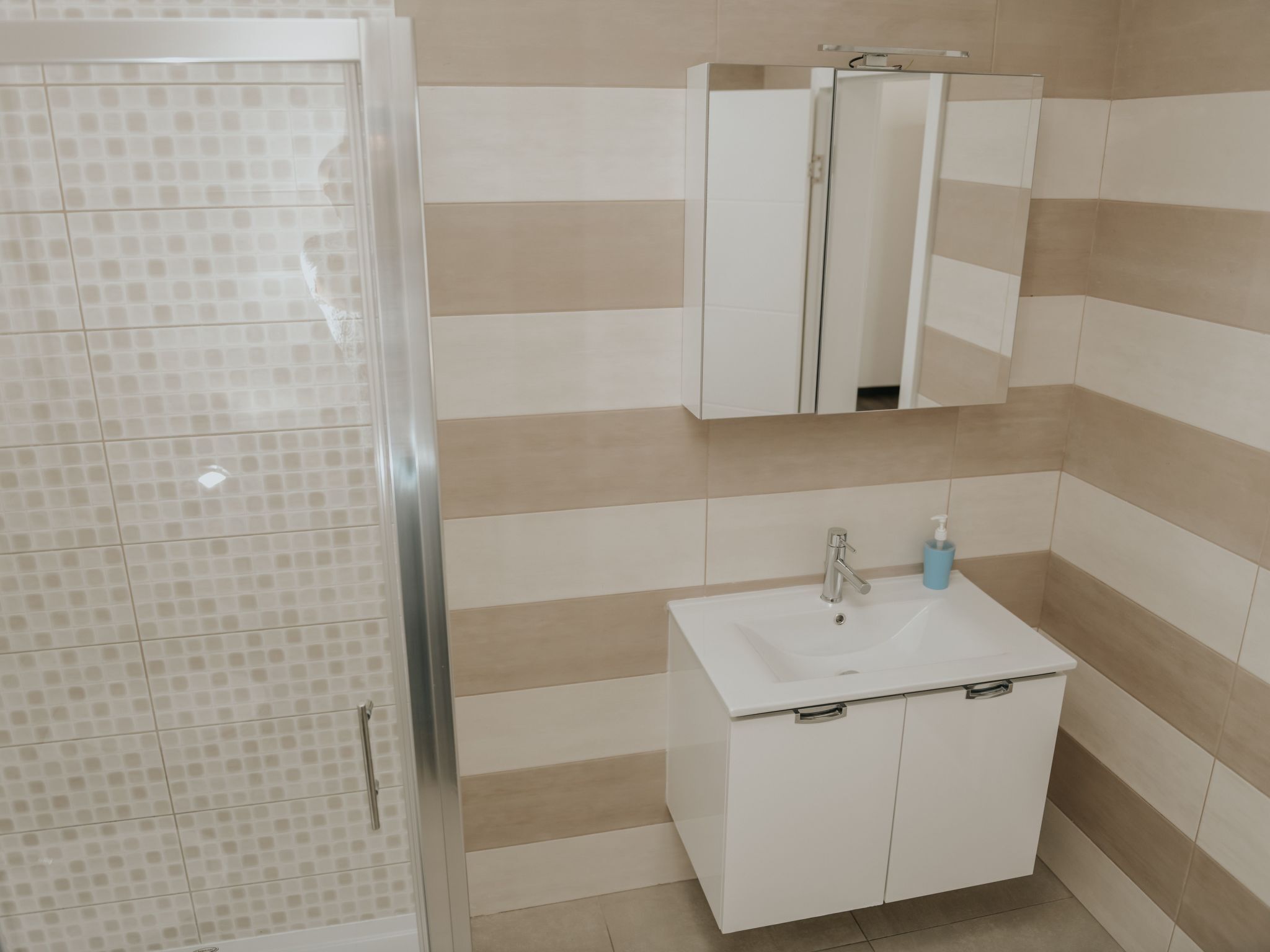 Ein Badezimmer mit Dusche, Waschbecken und Spiegel.