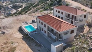 Un bâtiment à deux étages doté d’une piscine, entouré d’un paysage vallonné.