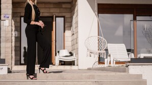 Une personne se tient sur les marches extérieures devant un bâtiment moderne doté d’une porte en verre et d’un fauteuil suspendu.