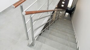 A modern staircase with metal railings and wooden handrails, leading to an interior space.