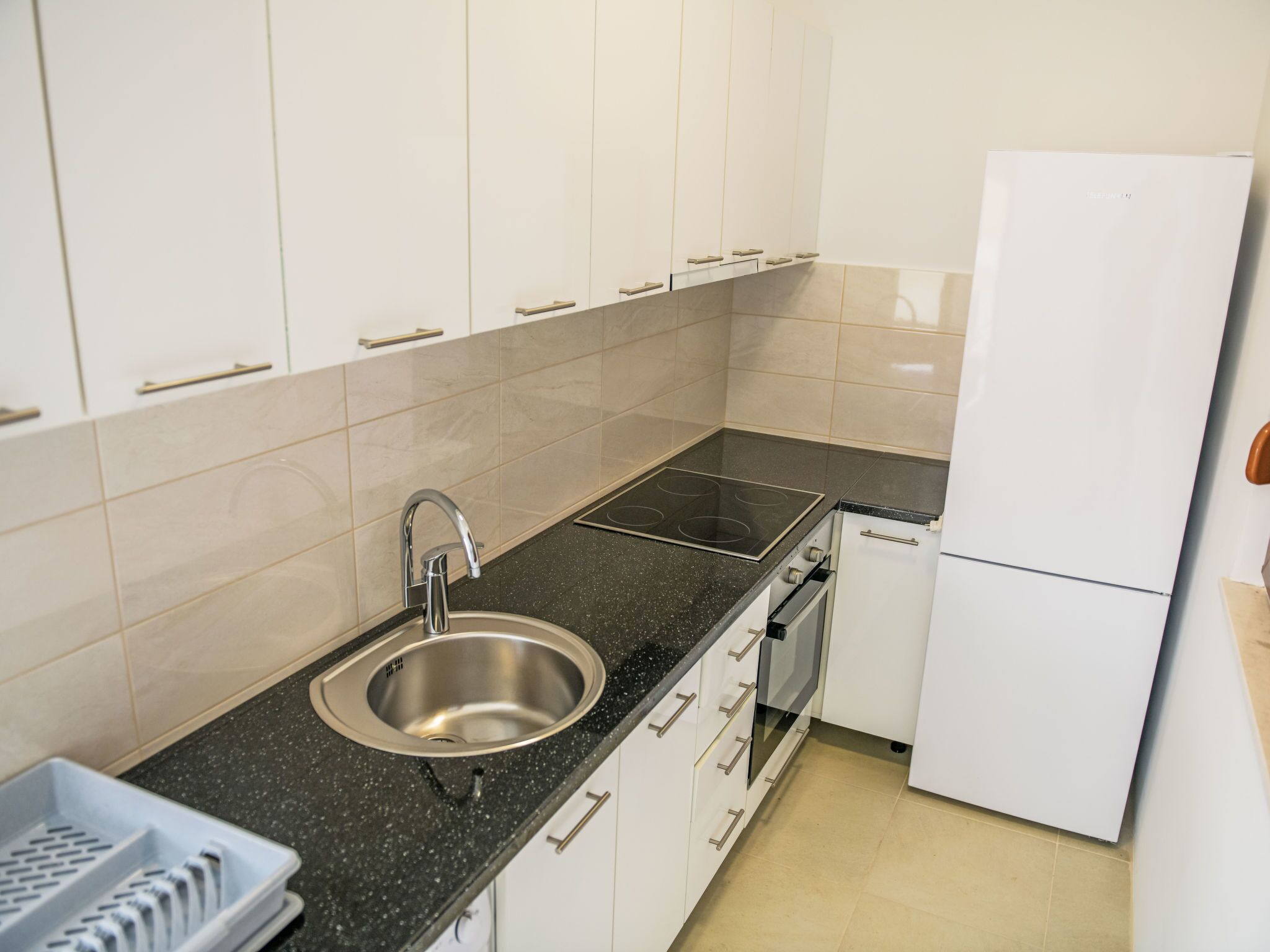 Een koelkast, een oven, een vaatwasser, kookgerei, borden en bestek