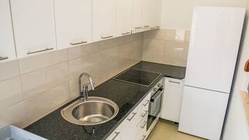 Een koelkast, een oven, een vaatwasser, kookgerei, borden en bestek