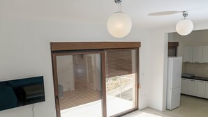 A modern kitchen with white cabinets, a refrigerator, and a ceiling fan.