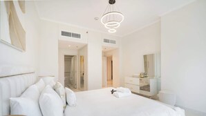 Una habitación de hotel moderna con una cama grande, una mesita de noche, un espejo y un armario.