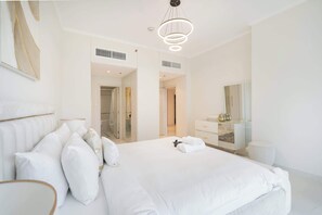 Ein modernes Hotelzimmer mit einem großen Bett, einem Nachttisch, einem Spiegel und einem Kleiderschrank.