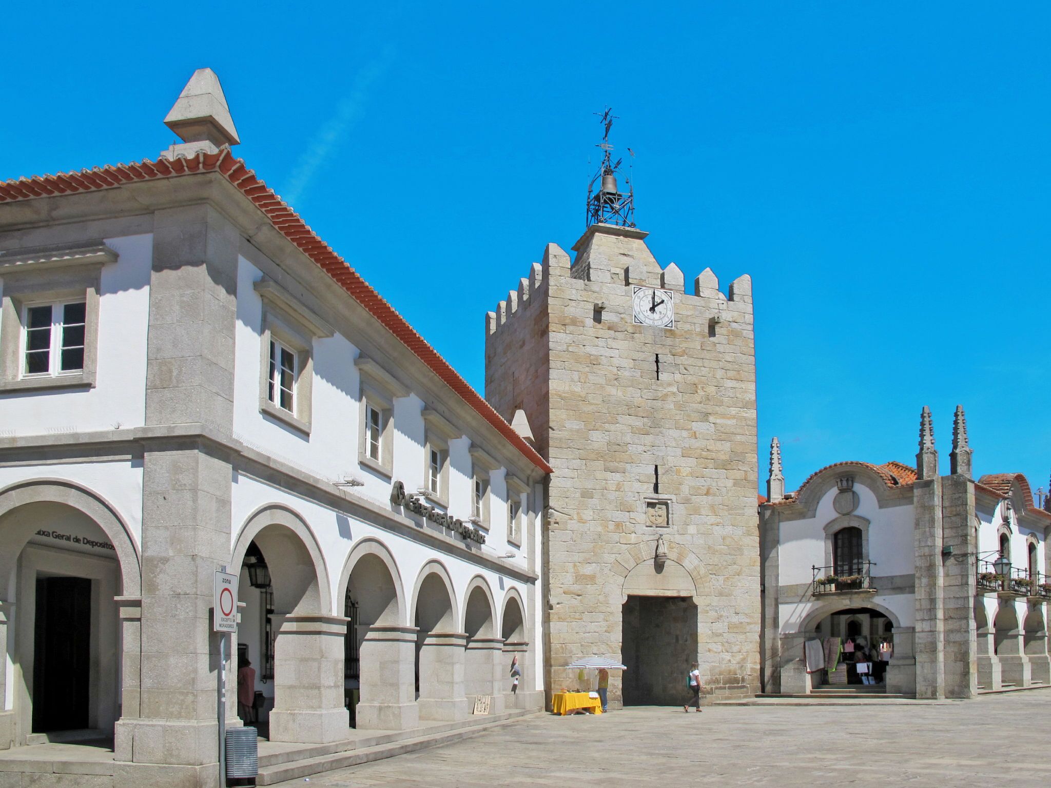 Un bâtiment historique doté d’une tour horlogée, de fenêtres en arc de cercle et d’un toit recouvert de tuiles.