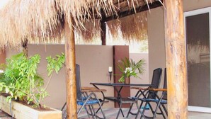 An outdoor patio with a table and chairs, surrounded by potted plants and a thatched roof structure. - Wohnung in Cas Grandi mit Schönem gemeinsamem Pool by Interhome (Jan Thiel)