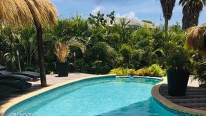A swimming pool with a tiled edge, surrounded by lush greenery and palm trees. - Wohnung in Cas Grandi mit Schönem gemeinsamem Pool by Interhome (Jan Thiel)