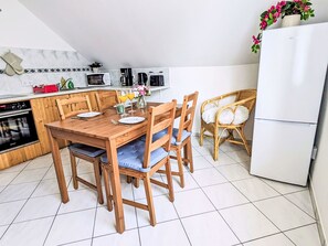 Una cocina con una mesa de madera, sillas, un refrigerador y un microondas.