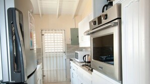 A kitchen with white cabinets, a stainless steel refrigerator, and an oven. - Gemütlicher karibischer Rückzugsort gegenüber dem Strand by Interhome (Sandy Lane)