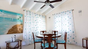 A dining area with a round table, four chairs, and a ceiling fan. - Gemütlicher karibischer Rückzugsort gegenüber dem Strand by Interhome (Sandy Lane)