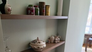 Ein Holzregal mit verschiedenen Küchenutensilien, darunter ein Teekessel, Tassen und Gläser.