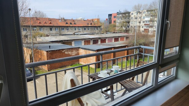 Ein Balkon mit Blick auf ein Wohngebiet, einschließlich Gebäude und Parkplatz.