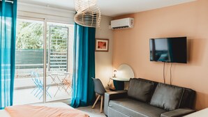 A modern hotel room with a sofa, a TV, and a dining area with chairs and a table. - Wohnung "Le Jardin de Corail" by Interhome (Saint-Gilles-les Bains)