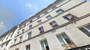 Un edificio de varios pisos con fachada plana, ventanas rectangulares y balcones con jardineras.