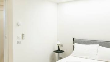 Ein ordentlich eingerichtetes Schlafzimmer mit einem Bett, einer Nachttischlampe und einer Wand-Klimaanlage.
