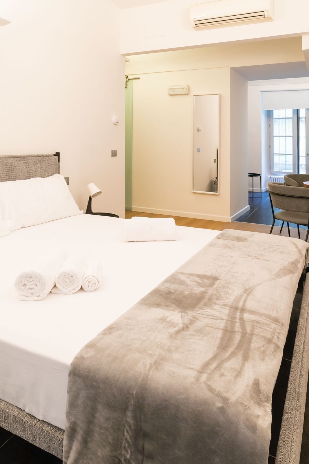 Camera d'albergo con un letto, una scrivania, una sedia e un bagno visibile attraverso una porta aperta.