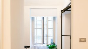 A modern interior with a dark tiled floor, a wooden table, and a chair. There is a radiator and a potted plant near the window. - Turin Central Carlo Felice (Turin)