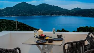 A dining table set with plates, cutlery, glasses, and a candle, overlooking a scenic view of a lake and mountains.