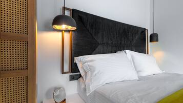 Et moderne hotelværelse med en stor seng, en sengegavl med geometriske mønstre, et natbord med et spejl og en vægmonteret lampe.