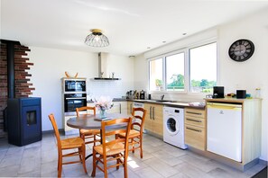 A modern kitchen with a dining area, built-in appliances, and large windows. - Holiday Home "Le Jardin" with Private Terrace and Wi-Fi (Lison)