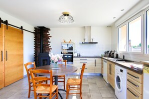 Une cuisine moderne avec un coin repas, un mur en briques, un lave-linge et une grande fenêtre.