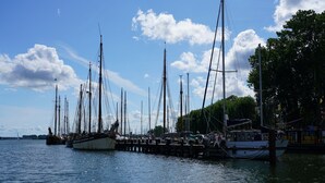A marina with multiple sailboats docked at wooden piers. - Passat - View of the river, terrace, garden, private parking space, fly screens (Olpenitzdorf)