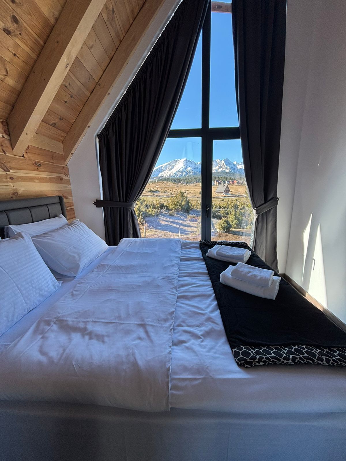 Una camera da letto con un'ampia finestra, un letto e vista sulle montagne.
