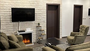 Una sala de estar moderna con una pared de piedra, un televisor de pantalla plana, chimenea y asientos cómodos.
