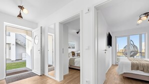 Ein geräumiges Schlafzimmer mit einem großen Bett, einem Fernseher und einem Balkon mit Sitzgelegenheit.