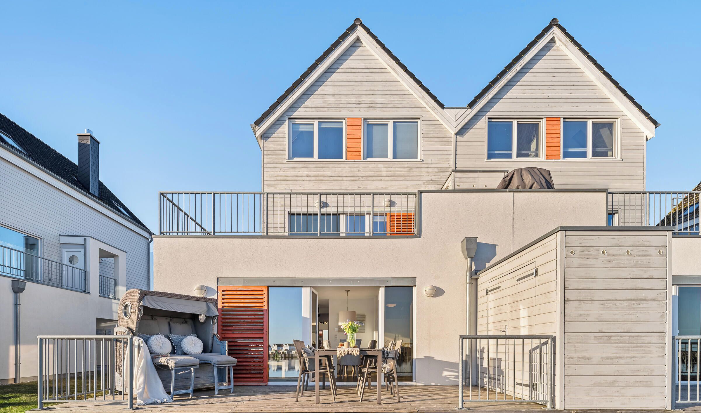 A two-story house with a balcony, a patio with outdoor furniture, and a garage.