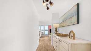 Ein Flur mit Holzboden, einer weißen Wand mit einem Gemälde, einer Lampe und einer Uhr.