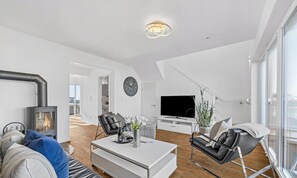 Ein modernes Wohnzimmer mit Kamin, Flachbildfernseher und Essbereich.