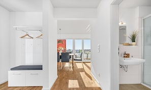 Eine moderne Wohnung mit Balkon, Essbereich und einem Badezimmer mit großem Waschbecken.