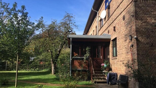 A brick building with a covered porch, a bench, and a garden area. - Kastanienblick by Interhome (Ziethen)