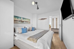 A modern bedroom with a bed, a painting, a ceiling lamp, and a television. - Landungsbrücke 28 - 1st row on the waterfront, infrared cabin, whirlpool tub (Olpenitz)